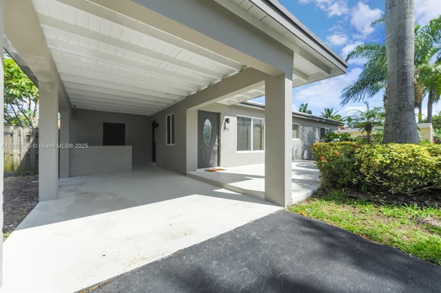 view of front of house with an attached carport, stucco siding, and asphalt driveway