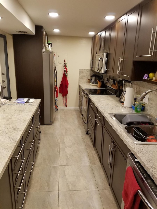 kitchen with stainless steel appliances, a sink, light countertops, recessed lighting, and dark brown cabinets