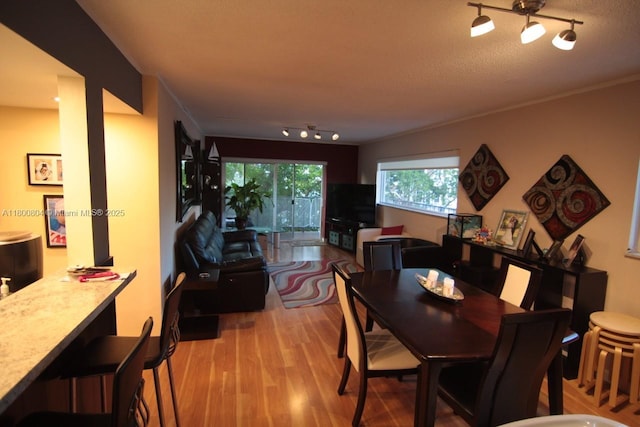 dining space with track lighting and wood finished floors