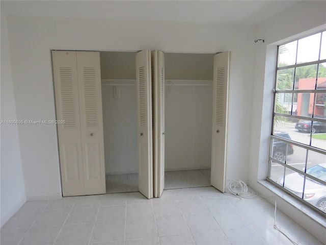 unfurnished bedroom featuring two closets and light tile patterned floors