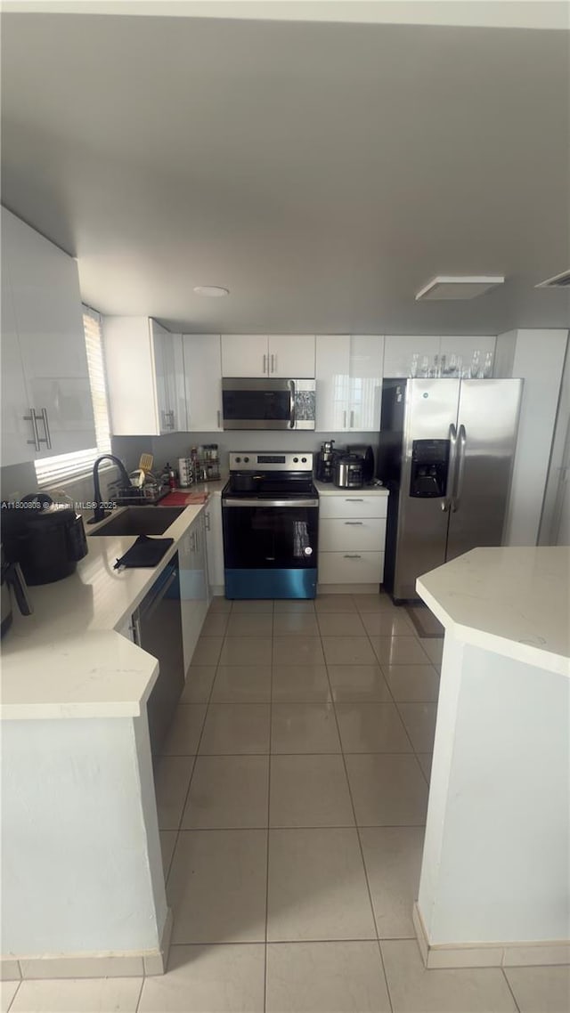 1351 NE Miami Gardens Dr Unit 1225E, Miami, FL 33179 - kitchen featuring appliances with stainless steel finishes, a sink, white cabinetry, light stone countertops, and light tile patterned flooring