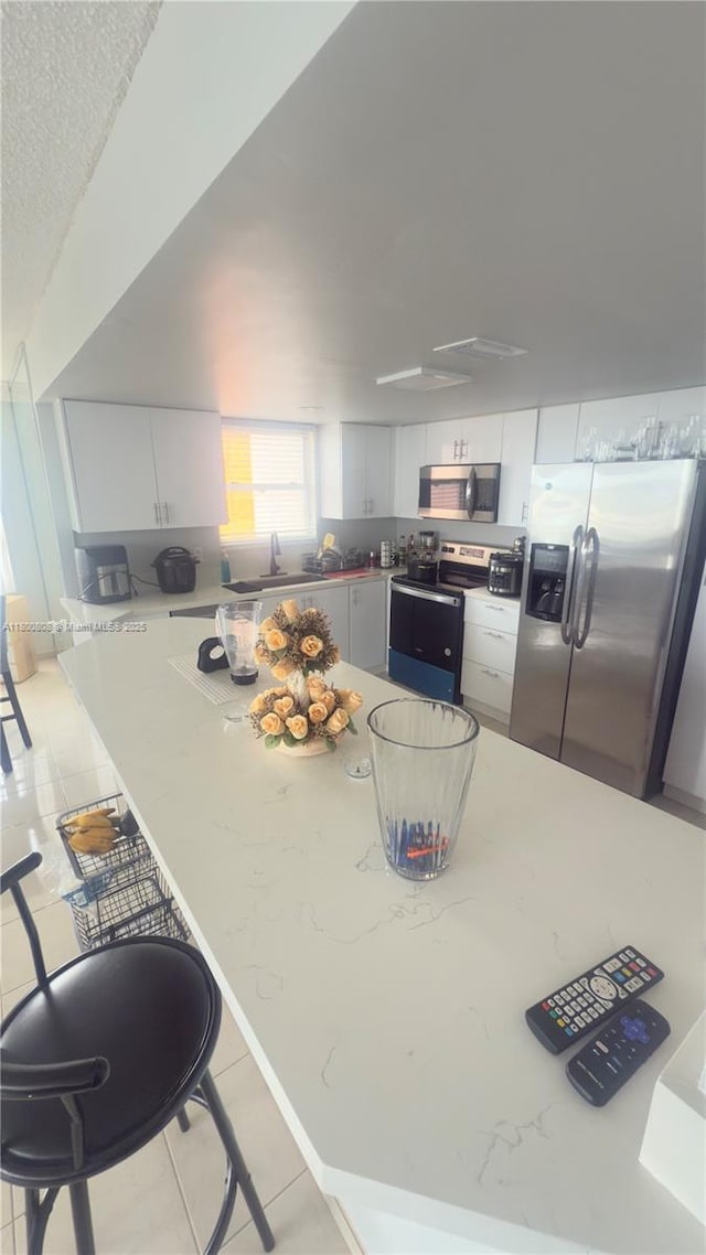 1351 NE Miami Gardens Dr Unit 1225E, Miami, FL 33179 - kitchen featuring stainless steel appliances, white cabinetry, light tile patterned floors, and a sink