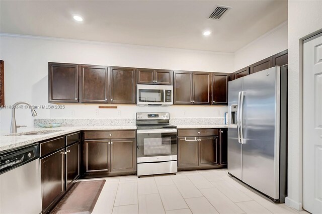 15073 SW 119th Ln, Miami, FL 33196 - kitchen featuring appliances with stainless steel finishes, a sink, crown molding, dark brown cabinets, and light stone countertops