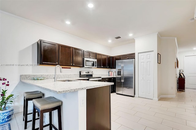 15073 SW 119th Ln, Miami, FL 33196 - kitchen with stainless steel appliances, a sink, a peninsula, dark brown cabinets, and a breakfast bar