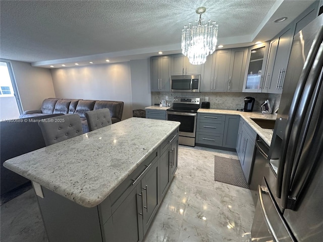 1865 S Ocean Dr Unit 17C, Hallandale Beach, FL 33009 - kitchen with appliances with stainless steel finishes, gray cabinets, a chandelier, tasteful backsplash, and a textured ceiling