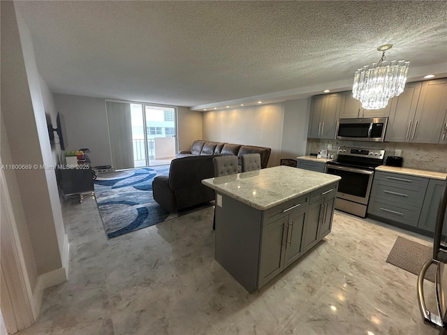 1865 S Ocean Dr Unit 17C, Hallandale Beach, FL 33009 - kitchen featuring stainless steel appliances, gray cabinetry, a center island, a textured ceiling, and open floor plan