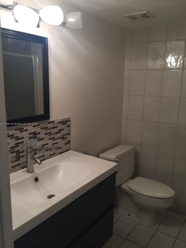 13499 Biscayne Blvd Unit 713, North Miami, FL 33181 - bathroom featuring vanity, toilet, backsplash, and tile walls