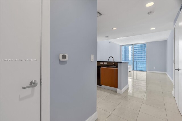 1060 Brickell Ave Unit 1811, Miami, FL 33131 - corridor featuring baseboards, expansive windows, light tile patterned floors, recessed lighting, and a sink