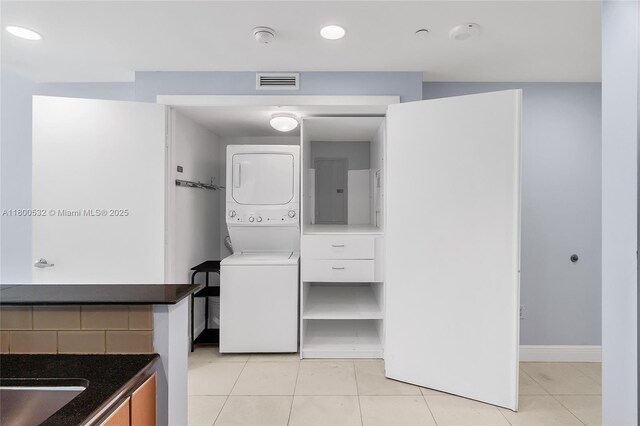 1060 Brickell Ave Unit 1811, Miami, FL 33131 - laundry area with stacked washing machine and dryer, light tile patterned floors, and baseboards