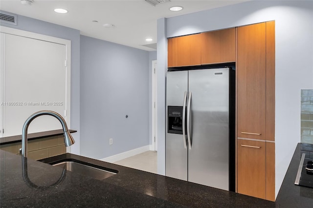 1060 Brickell Ave Unit 1811, Miami, FL 33131 - kitchen featuring stainless steel refrigerator with ice dispenser, a sink, dark stone countertops, brown cabinetry, and baseboards