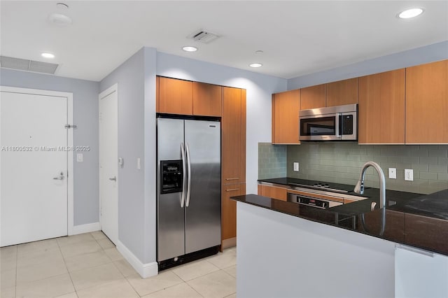1060 Brickell Ave Unit 1811, Miami, FL 33131 - kitchen featuring stainless steel appliances, brown cabinets, backsplash, a peninsula, and baseboards
