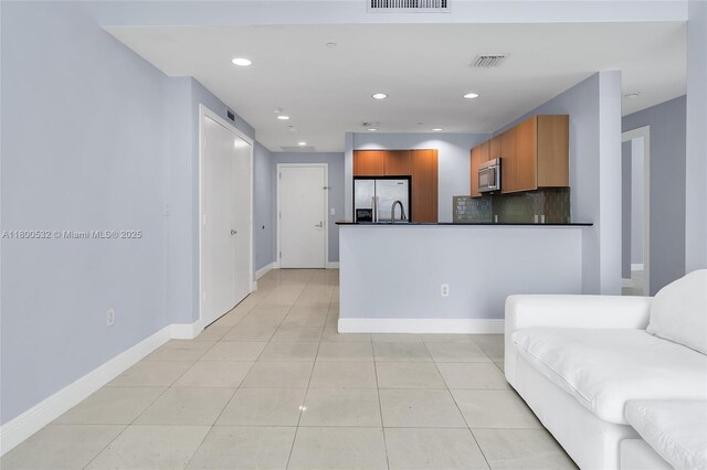 1060 Brickell Ave Unit 1811, Miami, FL 33131 - kitchen with appliances with stainless steel finishes, dark countertops, brown cabinets, a peninsula, and decorative backsplash
