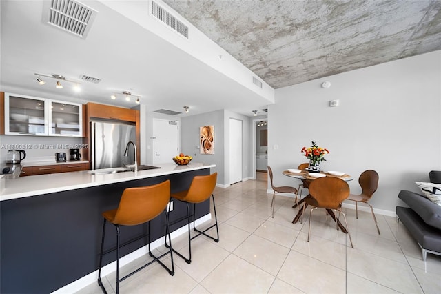 3250 NE 1st Ave Unit 806, Miami, FL 33137 - kitchen with freestanding refrigerator, a sink, glass insert cabinets, light countertops, and a kitchen bar