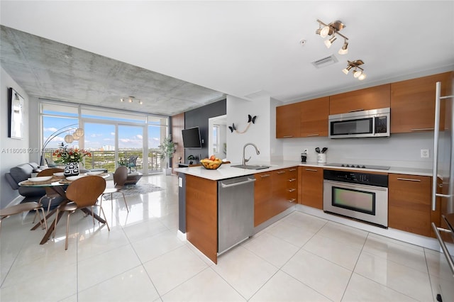 3250 NE 1st Ave Unit 806, Miami, FL 33137 - kitchen with appliances with stainless steel finishes, brown cabinetry, a sink, a peninsula, and rail lighting