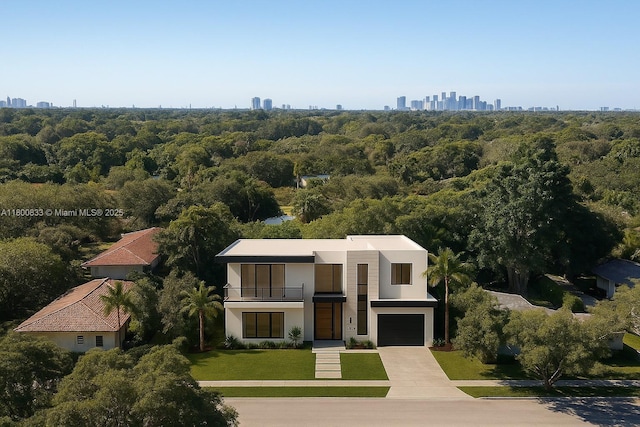 960 NE 121st St, Biscayne Park, FL 33161 - view of front of property featuring an attached garage, concrete driveway, stucco siding, a balcony, and a wooded view
