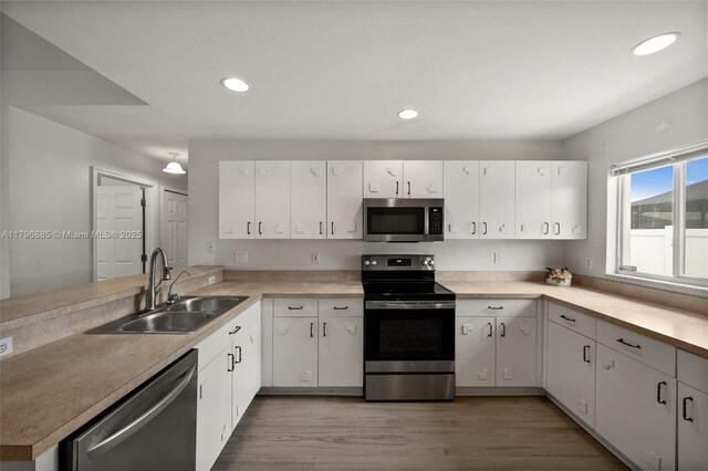 4344 Agualinda Blvd, Cape Coral, FL 33914 - kitchen featuring stainless steel appliances, a sink, a peninsula, light wood-type flooring, and light countertops