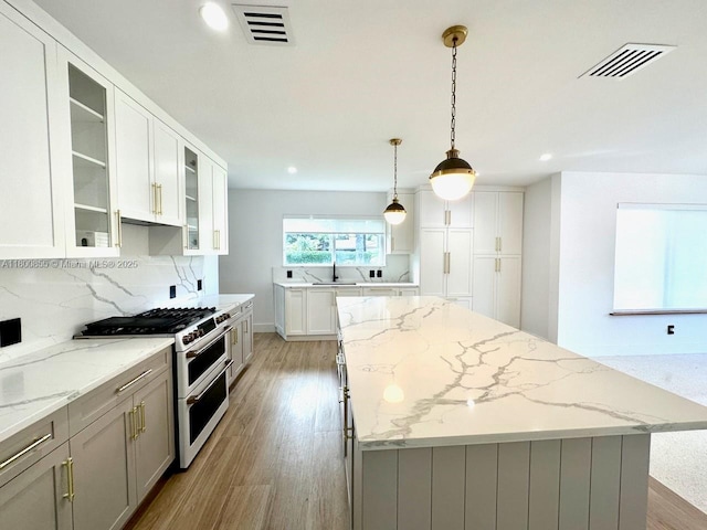 10361 NE 4th Ave, Miami Shores, FL 33138 - kitchen featuring range with two ovens, a center island, light wood-style floors, tasteful backsplash, and recessed lighting