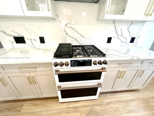 10361 NE 4th Ave, Miami Shores, FL 33138 - kitchen featuring range with gas cooktop, decorative backsplash, light stone countertops, light wood finished floors, and glass insert cabinets