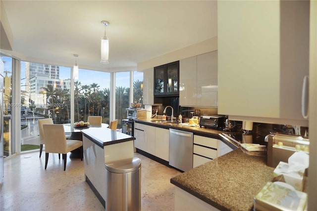 kitchen with stainless steel dishwasher, a sink, a wall of windows, hanging light fixtures, and modern cabinets