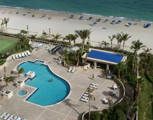 community pool with view of water and beach and a patio
