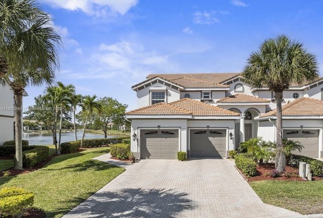 6893 Sterling Grns Unit 201, Naples, FL 34104 - mediterranean / spanish-style house featuring an attached garage, a water view, stucco siding, decorative driveway, and a front lawn
