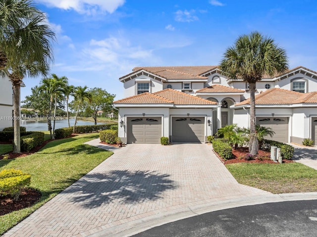 6893 Sterling Grns Unit 201, Naples, FL 34104 - mediterranean / spanish-style home with stucco siding, an attached garage, driveway, a front yard, and a water view