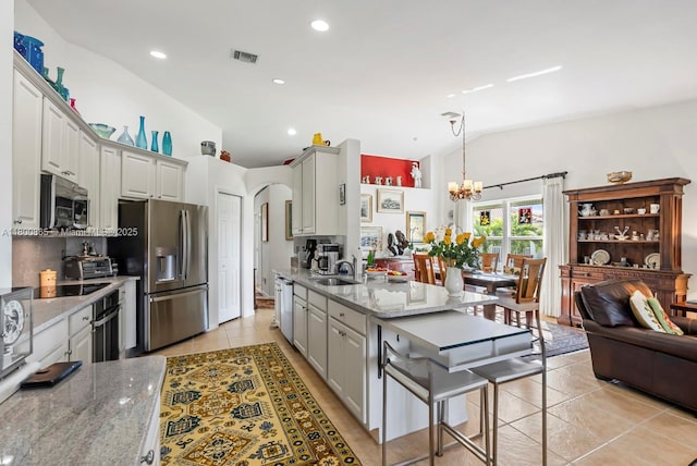 6893 Sterling Grns Unit 201, Naples, FL 34104 - kitchen featuring stainless steel appliances, light tile patterned floors, a chandelier, lofted ceiling, and a sink
