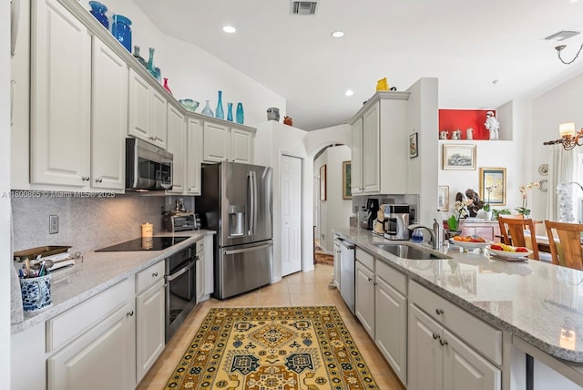 6893 Sterling Grns Unit 201, Naples, FL 34104 - kitchen with appliances with stainless steel finishes, a sink, tasteful backsplash, arched walkways, and light stone countertops