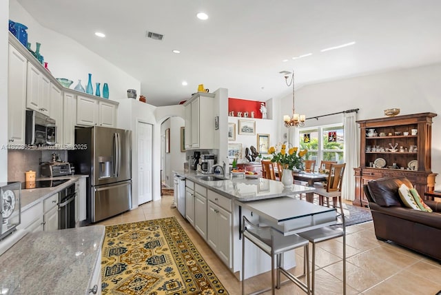 6893 Sterling Grns Unit 201, Naples, FL 34104 - kitchen featuring stainless steel appliances, light tile patterned floors, vaulted ceiling, a sink, and a chandelier