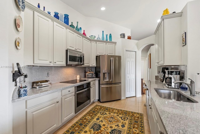 6893 Sterling Grns Unit 201, Naples, FL 34104 - kitchen featuring stainless steel appliances, a sink, arched walkways, decorative backsplash, and light stone counters