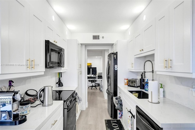 1201 S Ocean Dr Unit 404N, Hollywood, FL 33019 - kitchen with black appliances, white cabinets, a sink, and light wood-style floors