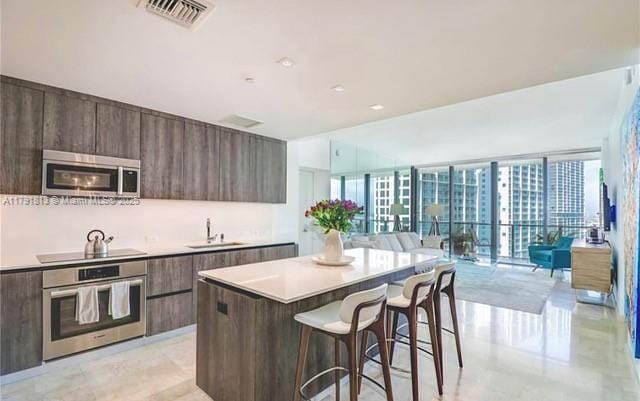 kitchen featuring appliances with stainless steel finishes, modern cabinets, light countertops, and a kitchen bar