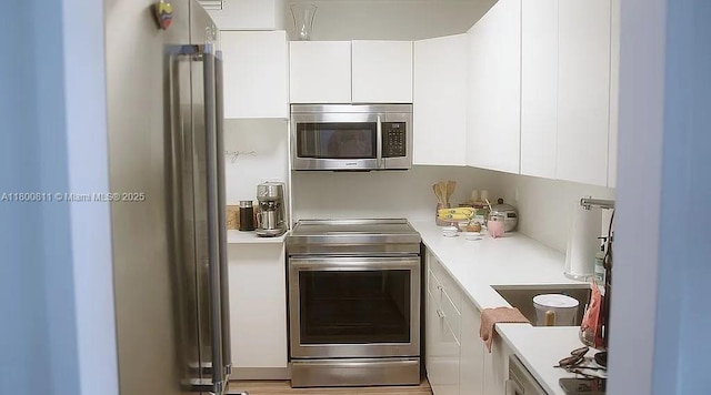 kitchen with stainless steel appliances, light countertops, and white cabinetry