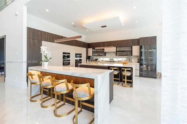 9625 Vescovato Way, Boca Raton, FL 33496 - kitchen featuring modern cabinets, a breakfast bar, a large island, a peninsula, and a towering ceiling
