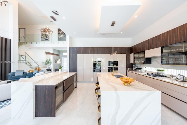 9625 Vescovato Way, Boca Raton, FL 33496 - kitchen featuring modern cabinets, a spacious island, stainless steel gas stovetop, dark brown cabinetry, and a high ceiling