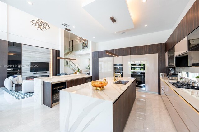 9625 Vescovato Way, Boca Raton, FL 33496 - kitchen with modern cabinets, a spacious island, gas stovetop, wine cooler, and dark brown cabinetry