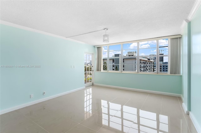 empty room with a textured ceiling, crown molding, baseboards, and tile patterned floors