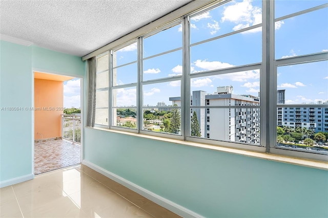 empty room featuring baseboards, a textured ceiling, a view of city, and tile patterned flooring