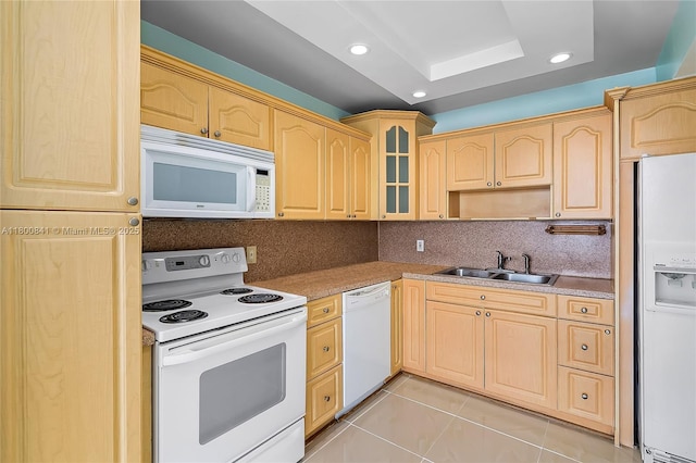 kitchen with white appliances, a sink, light brown cabinets, a raised ceiling, and recessed lighting