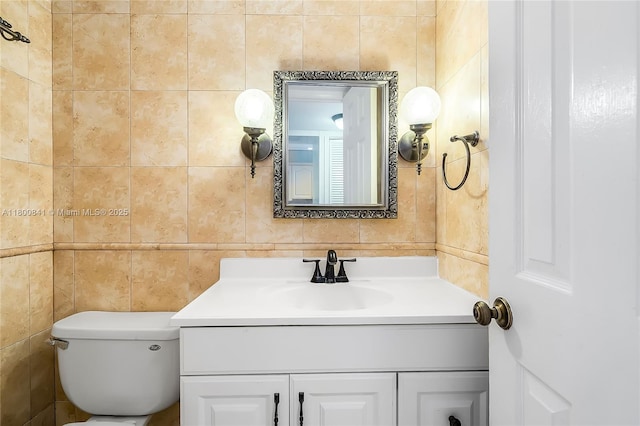 bathroom with tile walls, vanity, and toilet