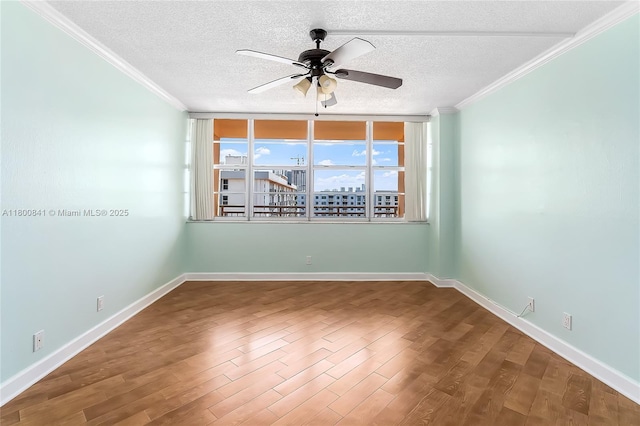 empty room featuring a ceiling fan, ornamental molding, wood finished floors, a textured ceiling, and baseboards