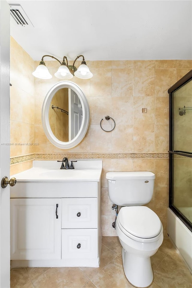 full bath featuring tile walls, vanity, toilet, shower / bath combination with glass door, and tile patterned flooring