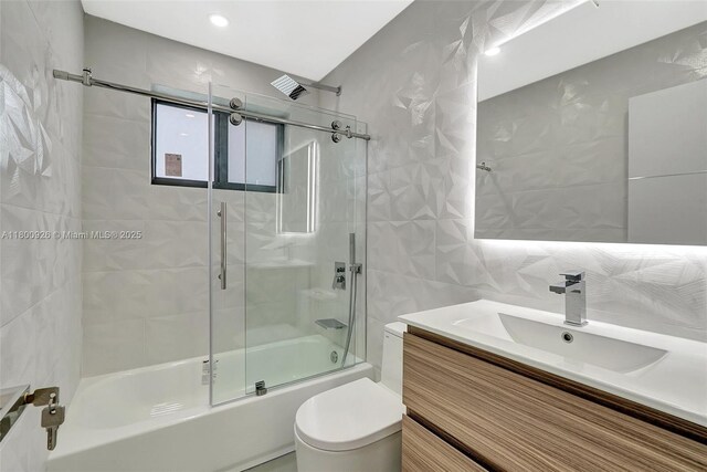129 NE 2nd Ave, Dania Beach, FL 33004 - full bathroom with vanity, combined bath / shower with glass door, tile walls, and toilet
