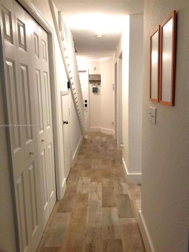 hallway featuring baseboards and light wood finished floors