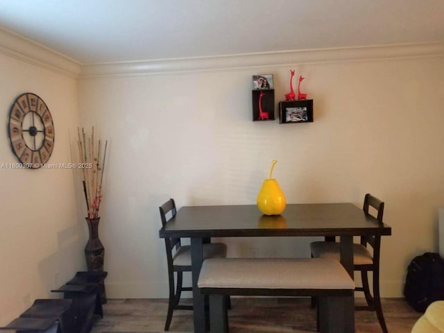 dining space featuring wood finished floors, ornamental molding, and baseboards