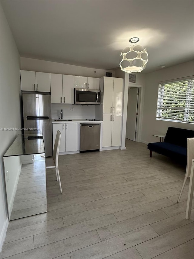 1601 Meridian Ave Unit 101, Miami Beach, FL 33139 - kitchen featuring stainless steel appliances, baseboards, light wood-style flooring, a sink, and white cabinetry