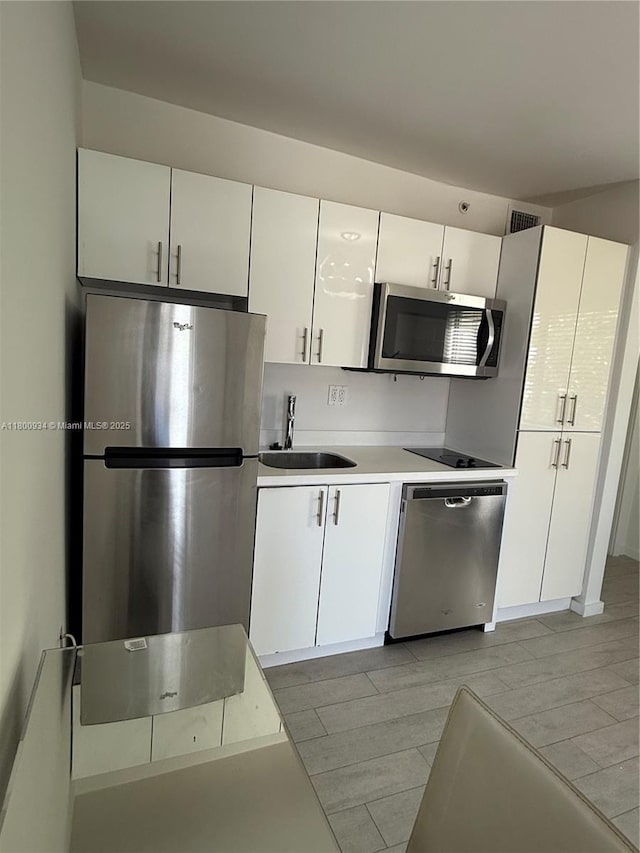 1601 Meridian Ave Unit 101, Miami Beach, FL 33139 - kitchen featuring stainless steel appliances, a sink, white cabinetry, light countertops, and light wood-type flooring