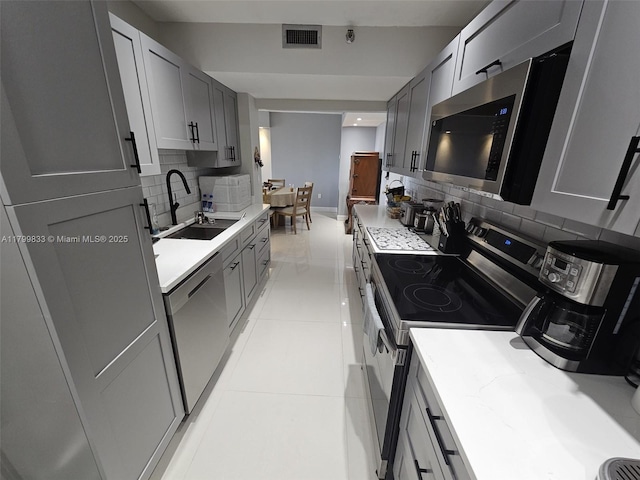3850 Washington St Unit 704, Hollywood, FL 33021 - kitchen featuring appliances with stainless steel finishes, a sink, gray cabinets, and decorative backsplash