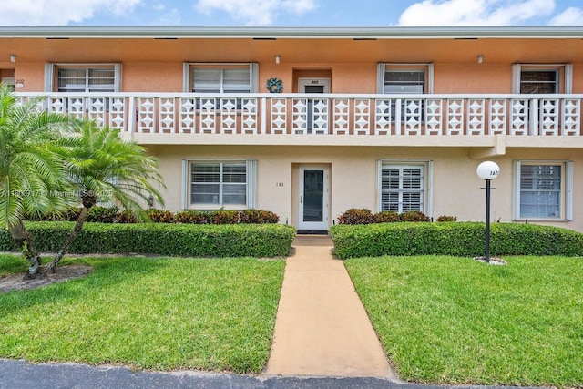 1621 NW 20th Ave Unit 203, Delray Beach, FL 33445 - view of front facade with stucco siding, a front yard, and a balcony