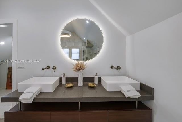 bathroom with lofted ceiling and double vanity